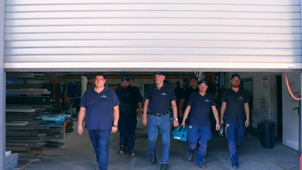 Das Team der Niederrhein Technik kommt unter dem geöffneten Rolltor aus der Halle