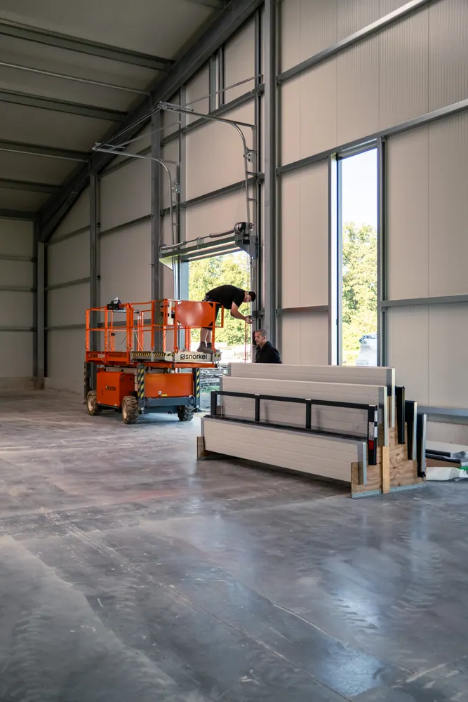 Neue Industriehalle mit Hubarbeitsbühne und bereitgestellten Torpaneelen