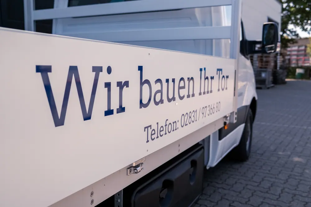 Schriftzug „Wir bauen Ihr Tor“ mit Telefonnummer auf dem Firmenwagen