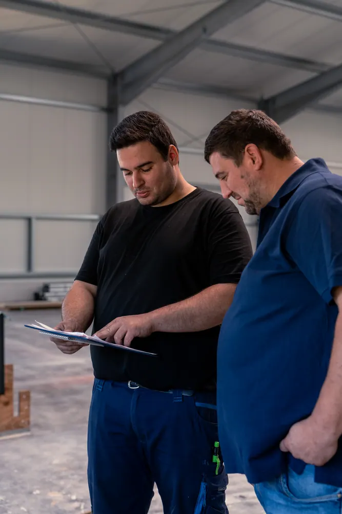 Zwei Mitarbeiter besprechen den Montageplan in der Halle