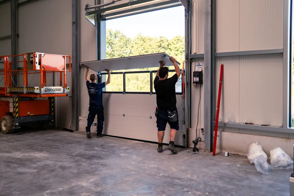 Zwei Monteure setzen ein Paneel mit Fensterreihe ein